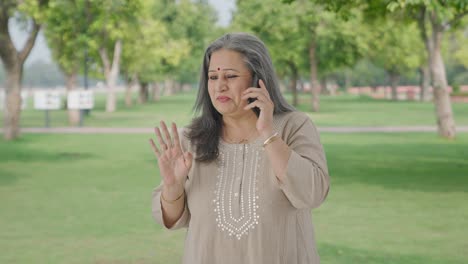 Cheerful-Indian-old-woman-talking-on-call-in-park