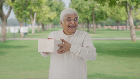 Happy-Indian-old-man-receiving-a-gift-in-park