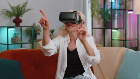 Senior-woman-use-virtual-reality-futuristic-technology-headset-play-simulation-3D-video-game-at-home