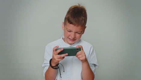 Worried-funny-addicted-toddler-boy-enthusiastically-playing-drive-racing-video-game-on-mobile-phone