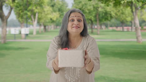 Happy-Indian-old-woman-giving-a-gift-in-park