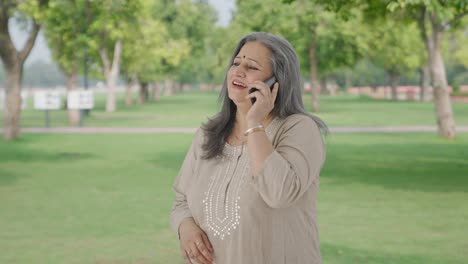 Happy-Indian-old-woman-talking-on-call-in-park