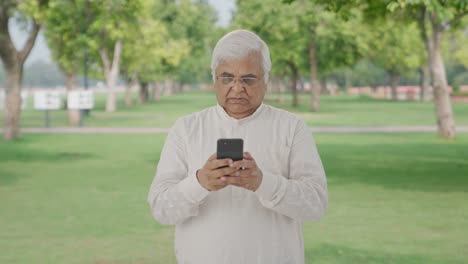 Angry-Indian-old-man-chatting-on-phone-in-park