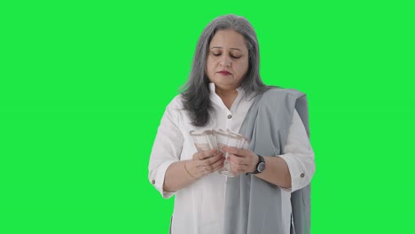 Indian-senior-businesswoman-counting-money-Green-screen