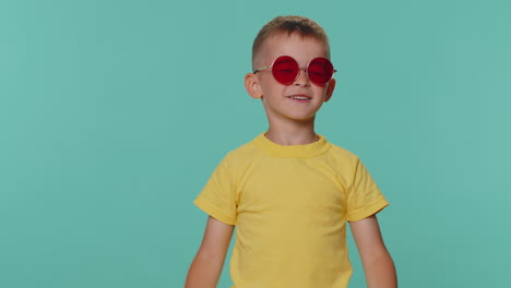 Retrato-De-Un-Seductor-Niño-Pequeño-Con-Camiseta-Y-Gafas-De-Sol-Rojas,-Sonrisa-Encantadora