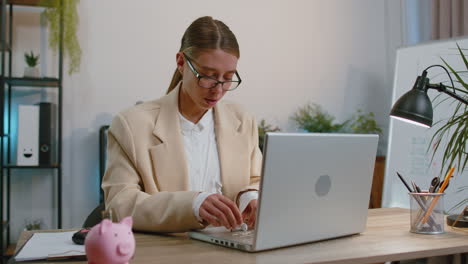 Businesswoman-working-on-laptop-at-office-wearing-earphones-listening-favorite-energetic-disco-music