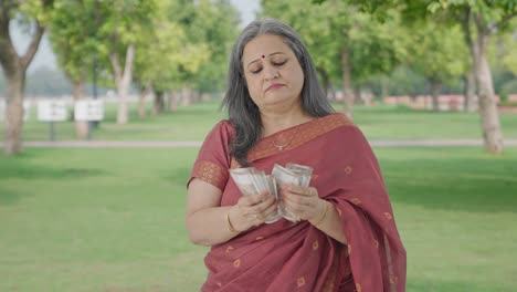 Indian-old-woman-counting-money-in-park