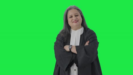 Happy-Indian-senior-female-lawyer-standing-crossed-hands-Green-screen