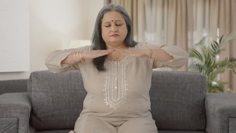 Relaxed-Indian-old-woman-doing-breathe-in-breathe-out-exercise