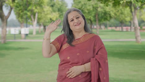 Happy-Indian-old-woman-waving-and-saying-Hello-in-park