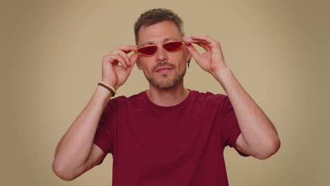 Alegre,-Barbudo,-Guapo-Y-Elegante-Joven-Con-Camiseta-Y-Gafas-De-Sol-Rojas-Sonriendo,-Mirando-La-Cámara