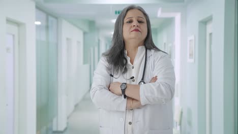 Confident-Indian-senior-female-doctor-standing-crossed-hands