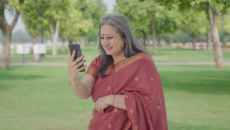 Happy-Indian-old-woman-talking-on-video-call-in-park