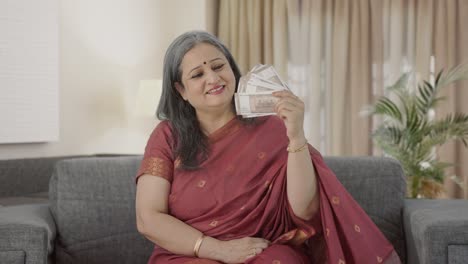 Happy-Indian-old-woman-using-money-as-fan