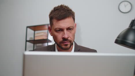 Close-up-businessman-freelancer-at-office-workplace-working-on-laptop-computer-sends-online-messages