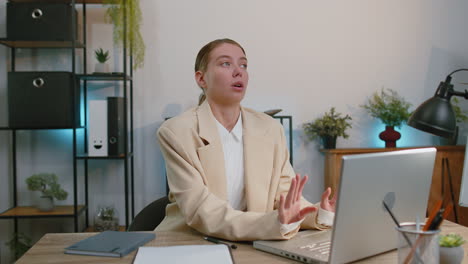 Businesswoman-working-on-laptop-meditating-doing-yoga-breathing-exercise-in-lotus-position-at-office