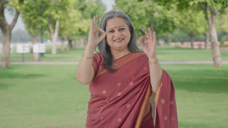 Happy-Indian-old-woman-showing-okay-sign-in-park