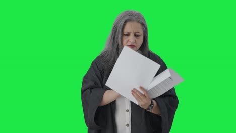 Indian-senior-female-lawyer-reading-case-reports-Green-screen