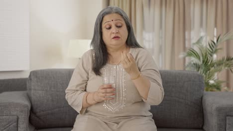 Sick-Indian-old-woman-taking-medicine-for-headache