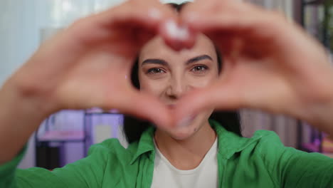 Young-woman-makes-symbol-of-love,-showing-heart-sign-to-camera,-express-romantic-positive-feelings