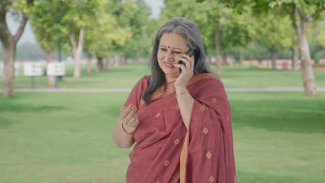 Happy-Indian-old-woman-talking-on-phone-in-park