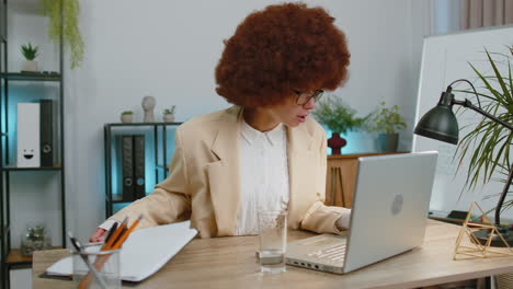 Focused-business-woman-girl-at-office-reads-social-media-news-accidentally-spilled-water-on-laptop