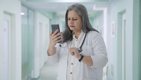 Indian-senior-female-doctor-scrolling-phone