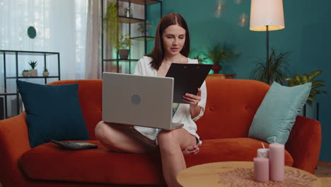 Young-businesswoman-working-with-laptop-computer-and-documents,-planning-expenses-budget-at-home