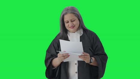 Happy-Indian-senior-female-lawyer-reading-case-reports-Green-screen