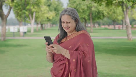 Glückliche-Alte-Indische-Frau-Im-Chat-Am-Telefon-Im-Park