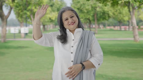 Happy-Indian-mother-saying-hello-and-waving-hand-in-park