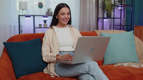 Woman-sitting-on-home-couch,-looking-at-camera,-making-video-conference-call-with-friends-or-family