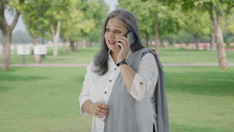 Glückliche-Indische-Mutter-Telefoniert-Im-Park