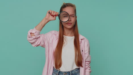 Researcher-scientist-girl-holding-magnifying-glass-near-face,-looking-to-camera-with-big-zoomed-eye