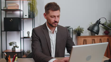 Business-smiling-man-closing-laptop-computer-after-finishing-online-work-remote-job-from-home-office