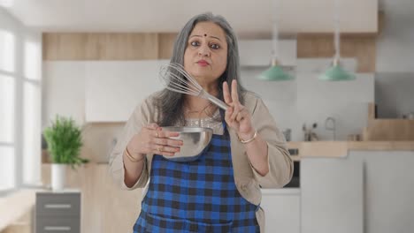 Indian-aged-housewife-talking-to-someone-while-making-food