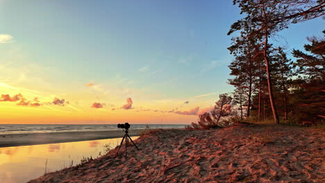 Camera-on-tripod-on-a-beautiful-beach-during-sunset-at-Irbes-ieteka-with-copy-space