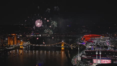 Cincinnati-Ohio-Aerial-v48-flyover-captures-bridges-over-the-river,-waterfront-ball-park-and-downtown-cityscape-with-vivid-fireworks-lighting-up-the-night-sky---Shot-with-Inspire-3-8k---September-2023