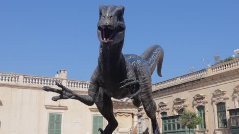 Low-view-of-a-statue-of-a-blue-velociraptor-dinosaur-in-Valletta,-Malta