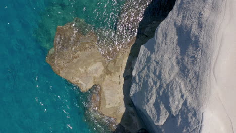 Aerial:-Rising-top-down-drone-shot-of-white-rocks-and-turquoise-water-on-Sarakiniko-Beach-in-Milos-Island,-Cyclades,-Greece