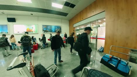 Tourists-arriving-at-Taiwan-International-Airport,-packing-luggage-onto-trolley-next-to-luggage-belt