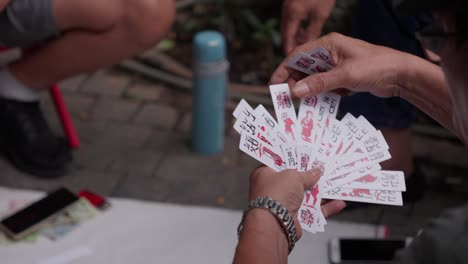 Old-man-play-Tam-Cuc-traditional-card-game-on-roadside,-slow-motion