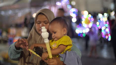 Asian-woman,-hijab-traditional-dress,-young-child,-sweet-treat,-urban-scene