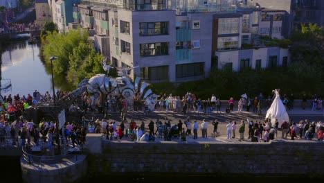 Aerial-tracking-shot-of-the-stunning-Pegasus-parade-crossing-a-bridge-filled-with-spectators