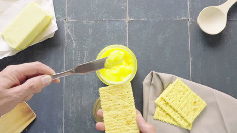 Man's-hand-spreading-ghee-butter-with-a-knife-on-a-soda-cracker