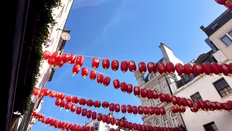 Faroles-Chinos-Rojos-Colgados-En-Una-Calle-De-Chinatown,-Londres,-Contra-Un-Cielo-Azul-Brillante