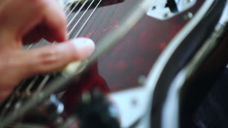 Wunderschöne-Zeitlupen-Detailaufnahme-Von-Händen,-Die-In-Einem-Aufnahmestudio-Rhythmisch-Die-Saiten-Einer-E-Gitarre-Zupfen,-Mit-Natürlichem-Licht,-Das-Vom-Balkon-Hereinfällt