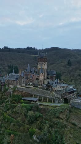 Aerial-vertical-orbit-view-of-Reichsburg-Cochem-Castle,-Rhineland-Palatinate,-Germany-on-a-beautiful-cloudy-sky