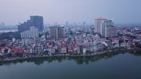 Dieses-Filmmaterial-Fängt-Die-Abendliche-Skyline-Von-Hanoi,-Vietnam-Ein-Und-Zeigt-Eine-Mischung-Aus-Hochhäusern-Und-Wohngebieten-Entlang-Eines-Ruhigen-Gewässers