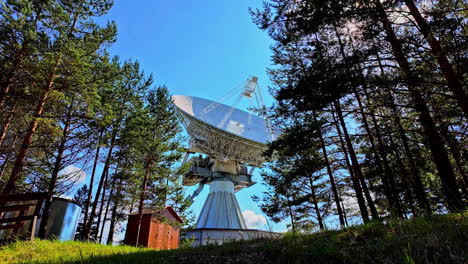 Exterior-view-of-the-Irbene-radio-telescope-standing-tall-amidst-deep-woodland,-highlighting-its-massive-structure-and-technological-significance